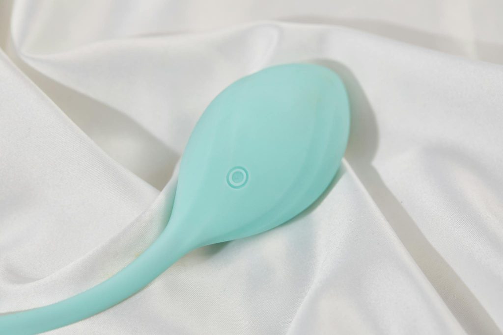A stylish teal vibrator on smooth white silk fabric, perfect for adult lifestyle imagery.