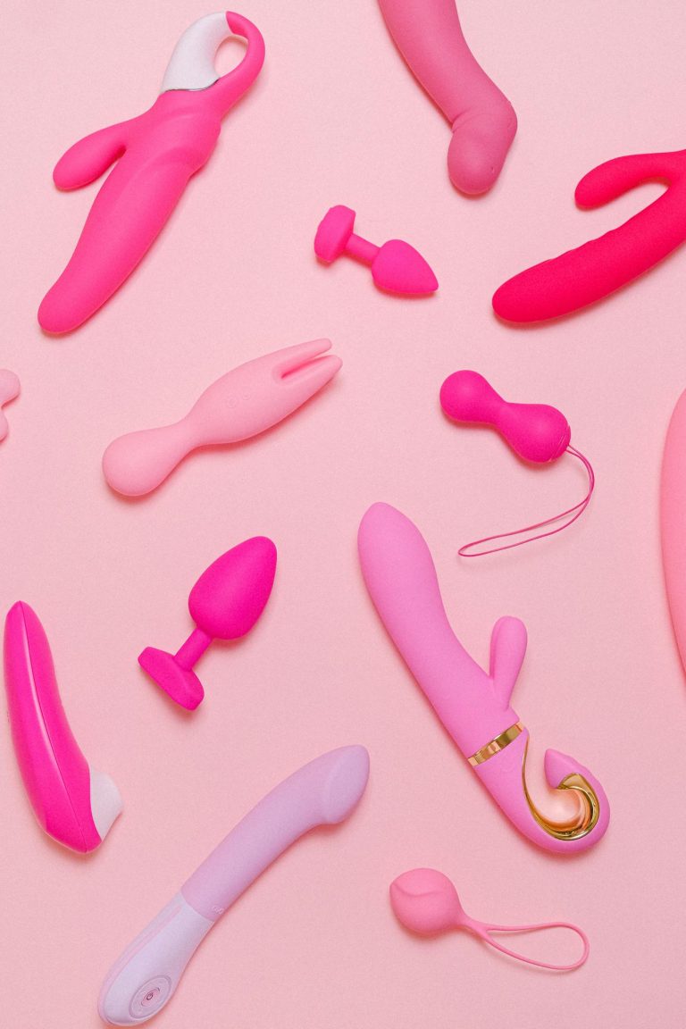 Explore a variety of pink adult toys including vibrators, silicone accessories, and more on a pastel background.