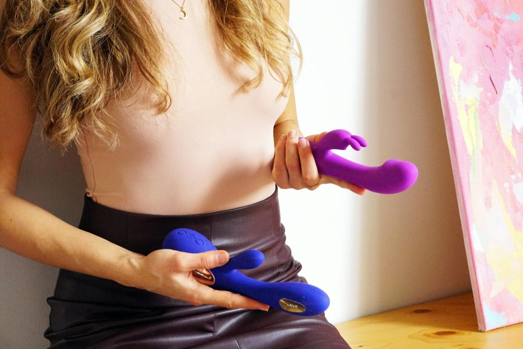 Person holding vibrant personal massagers in a stylish indoor setting, showcasing modern adult tools.