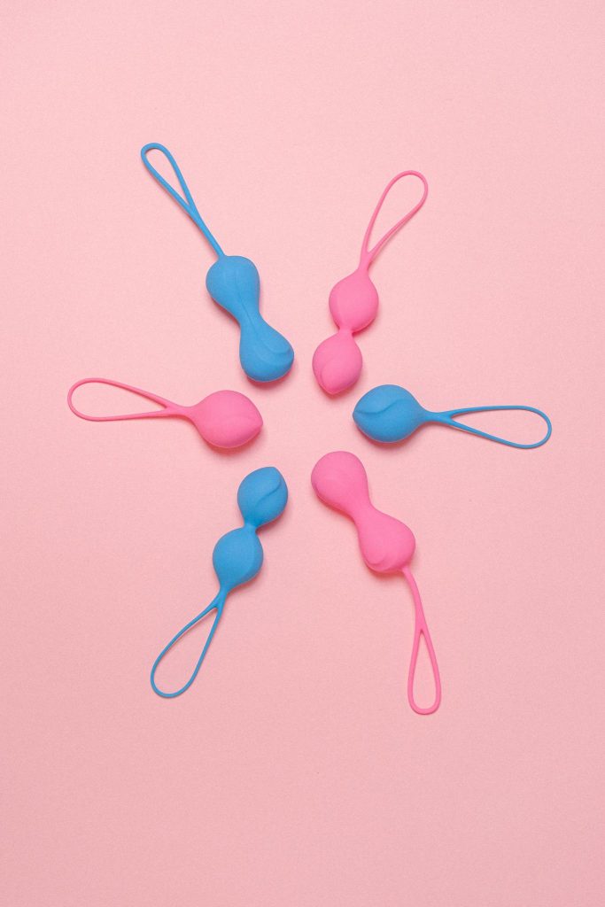 Stylish arrangement of blue and pink silicone Ben Wa balls against a pink backdrop.